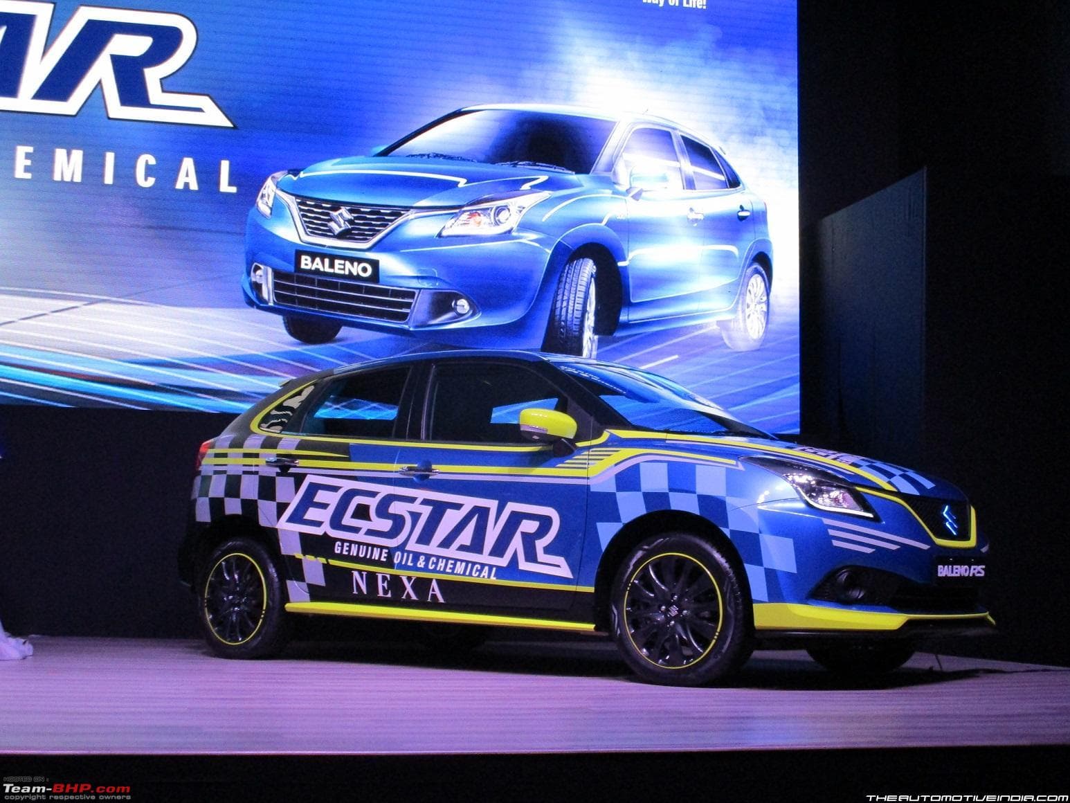 Suzuki Baleno RS finished in a blue, black and yellow ECSTAR livery, on stage at the ECSTAR brand launch
