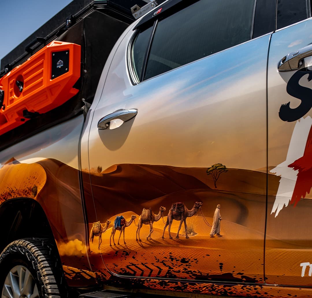 Custom desert-themed camel caravan graphic wrap on a Toyota Hilux door, a bespoke IDE One Off Build