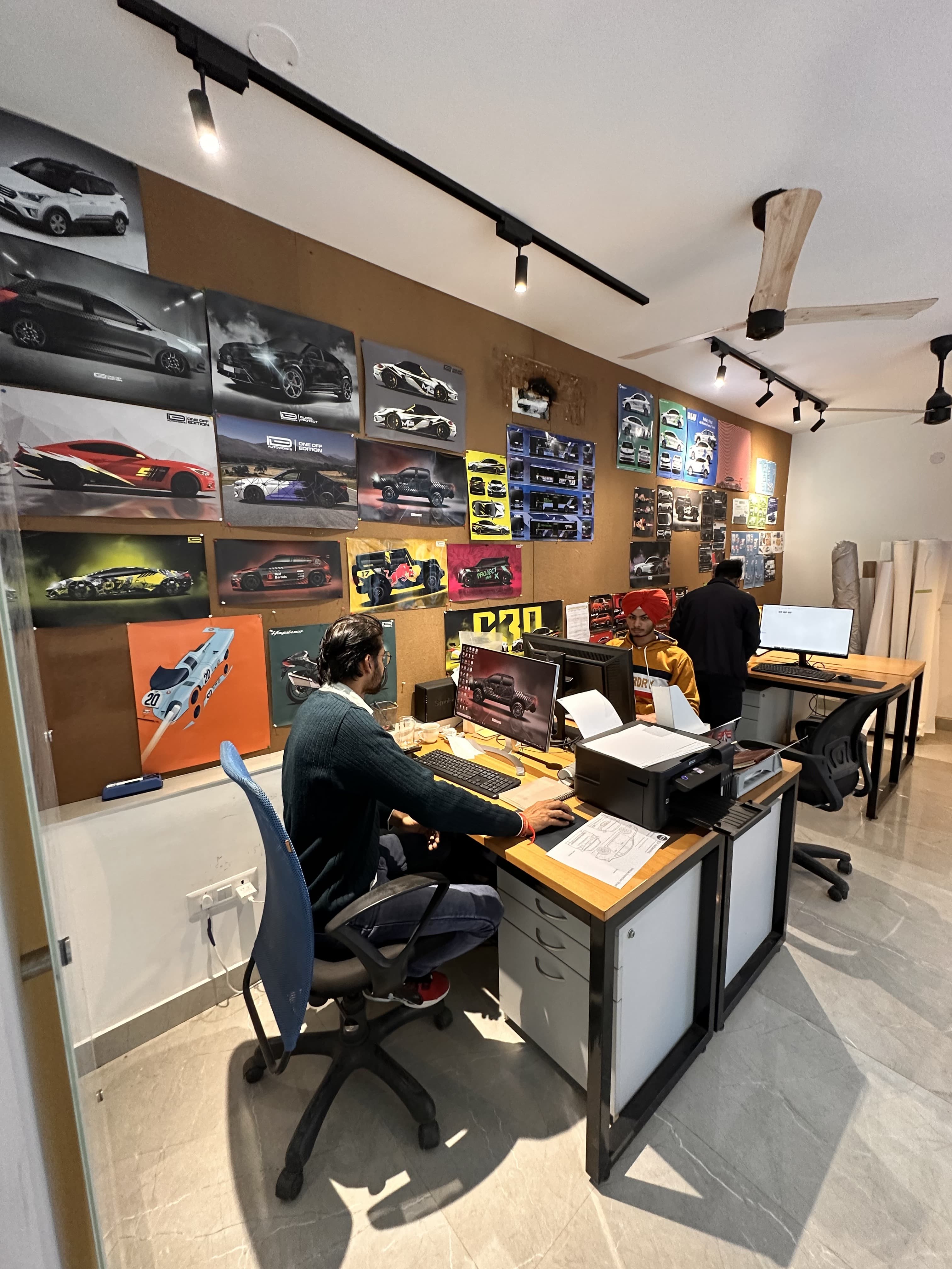 The IDE design team at work in the studio, surrounded by a wall of past project posters