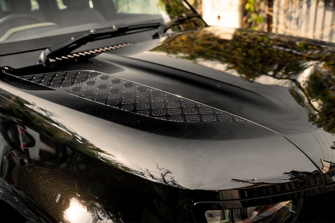 Gloss paint protection film on a black SUV's mirror and hood